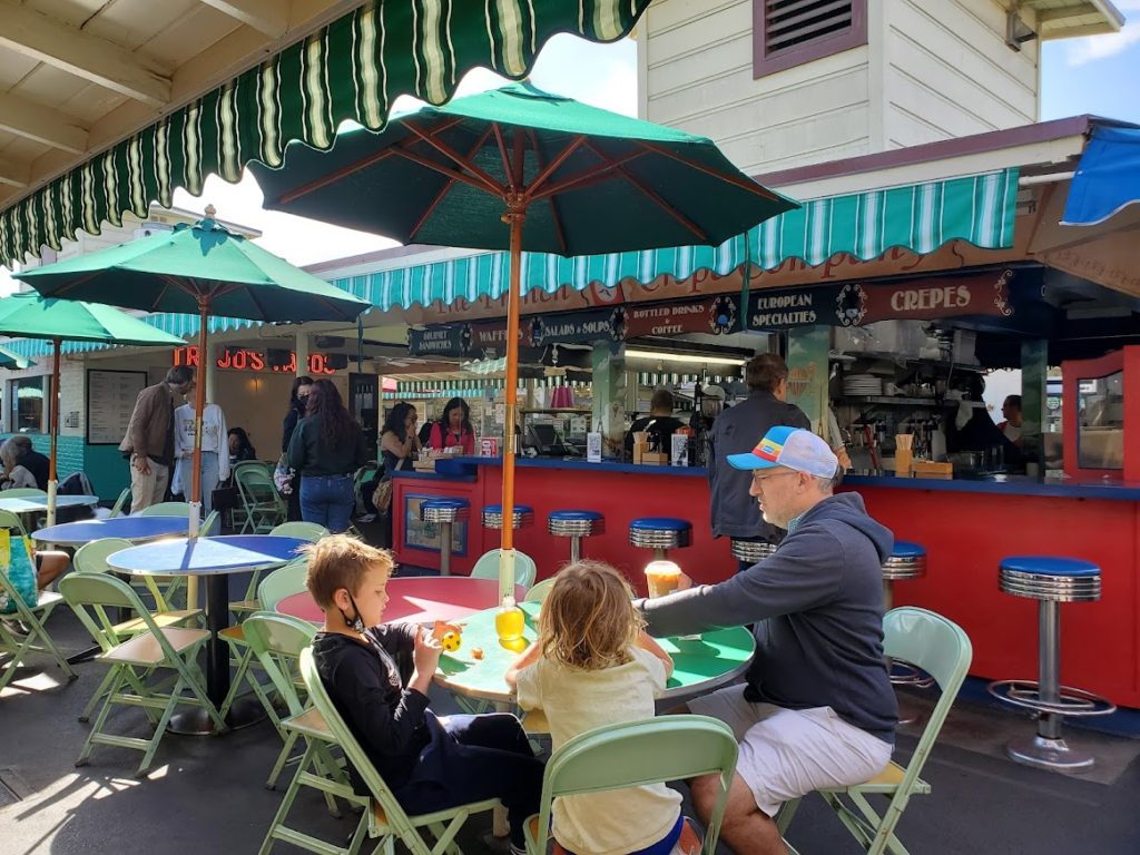 A family enjoying a meal at outdoor tables at the Farmer's Market LA.